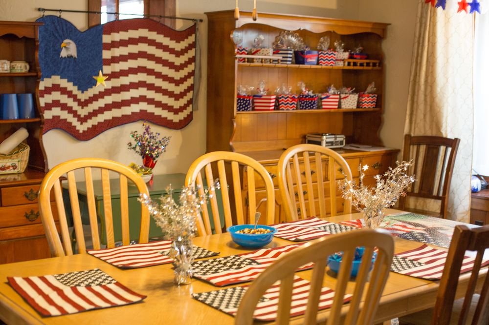 The Newbridge dining room set for a holiday meal, with an American flag quilt on the wall and star-spangled placemats